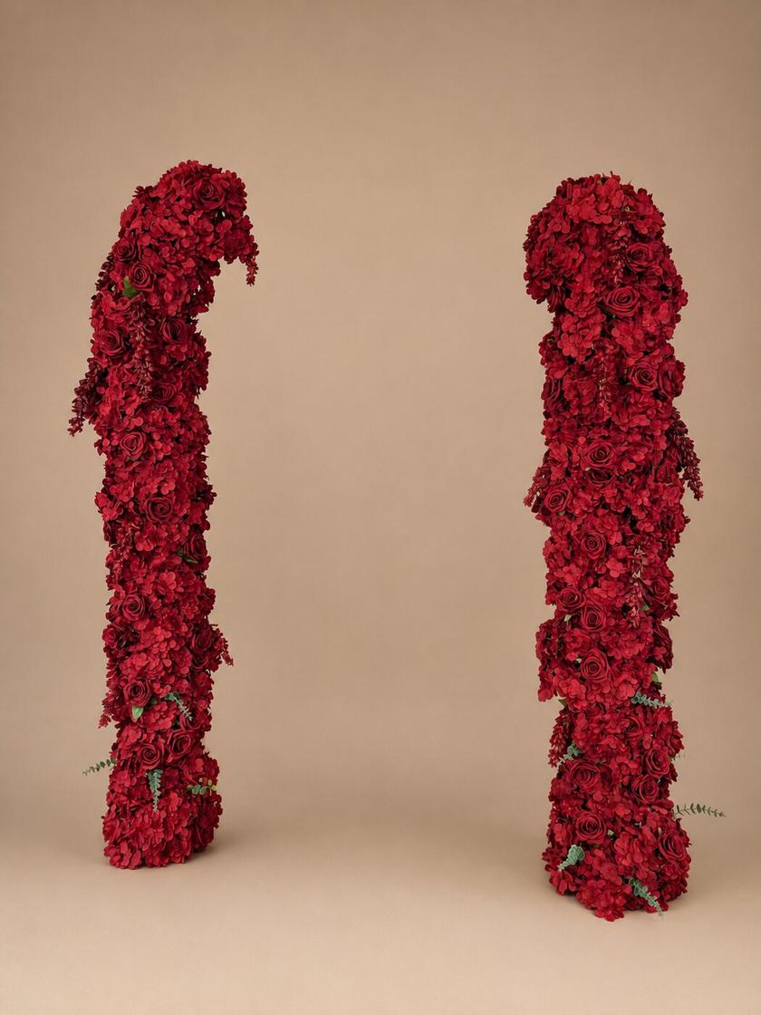Deep red floral arch towers with roses, hydrangea, and trailing greenery